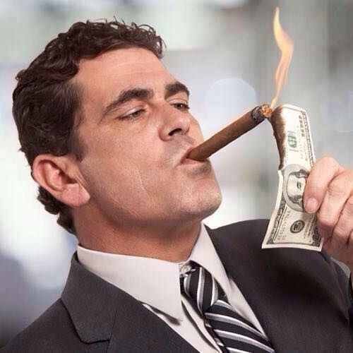 Мужчина прикуривает сигару от доллара